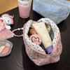 A pink leopard print cosmetic bag with a plush lining containing various beauty products and a glass of liquid.