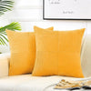 A set of two mustard yellow corduroy patchwork throw pillows resting on a light-colored sofa.