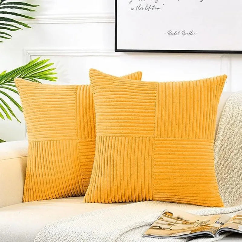 A set of two mustard yellow corduroy patchwork throw pillows resting on a light-colored sofa.