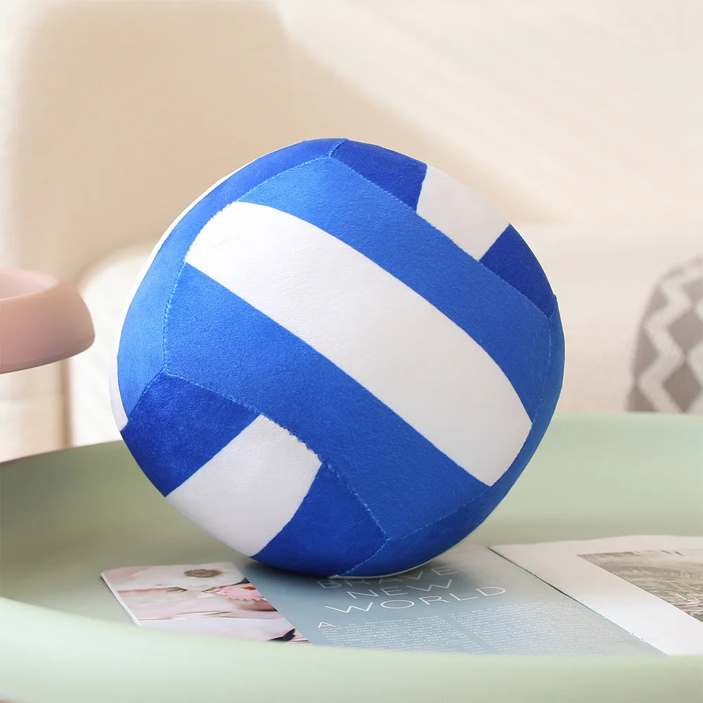 A blue and white striped simulation volleyball plush toy resting on a light green surface.