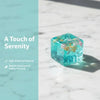 A clear blue crystal with iridescent inclusions resting on a white marble surface.