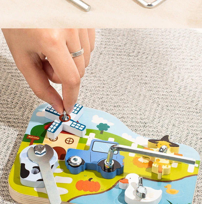 A hand is assembling a wooden farm animal toy featuring a truck, pumpkin, and other elements with a screwdriver and wrench.