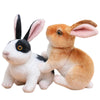 A white and black plush rabbit stuffed animal sitting on a white background.