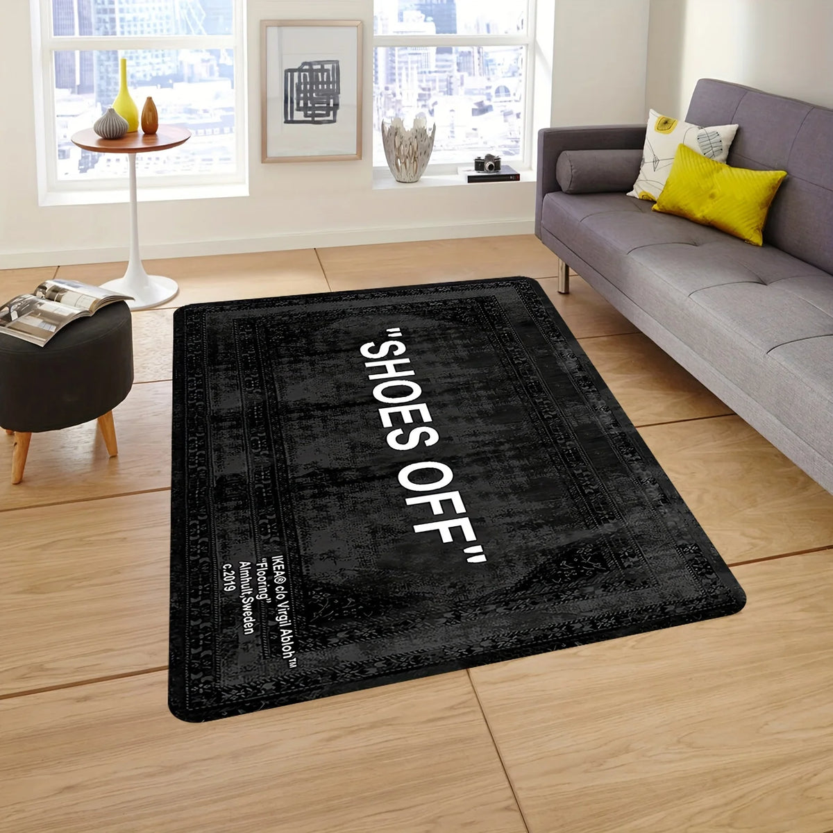 A black minimalist doormat with the text SHOES OFF on a light wood floor.