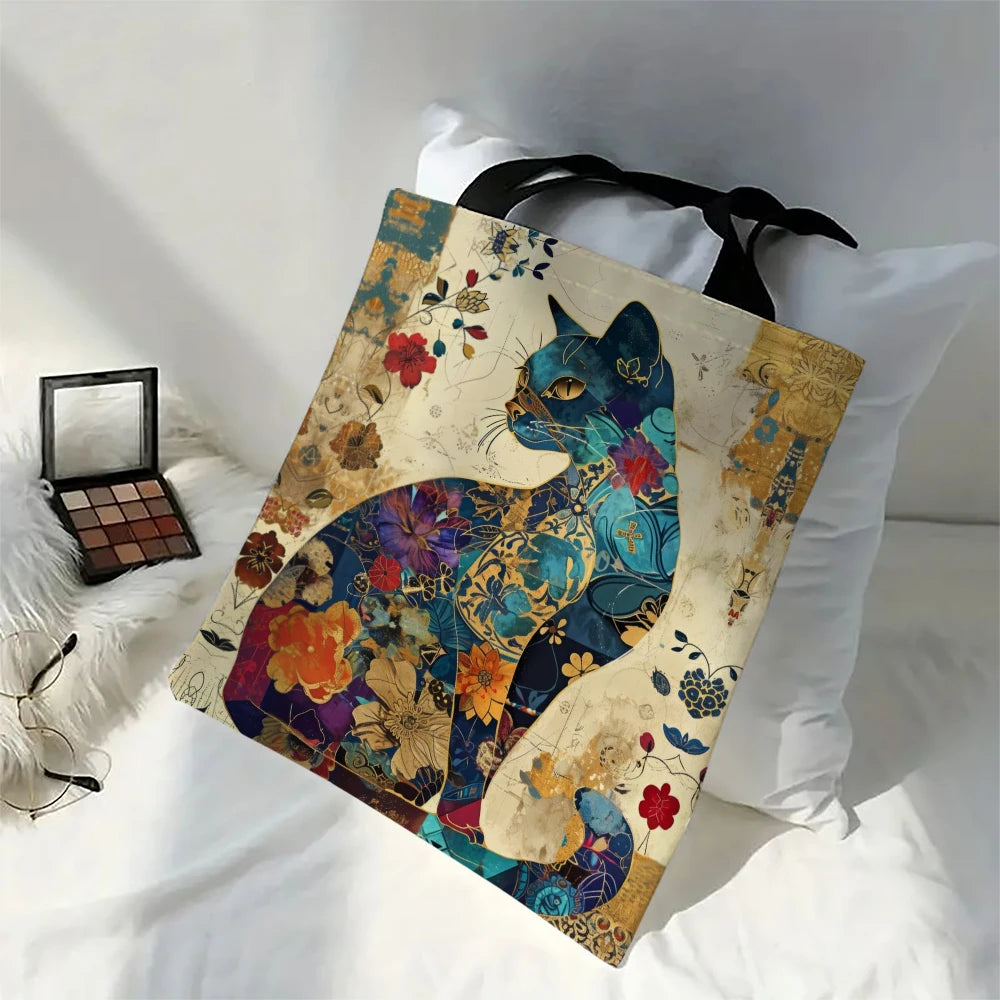A canvas tote bag featuring a watercolor floral cat design in blue, purple, and gold tones.