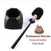 A novelty toilet brush featuring a small figure of Emmanuel Macron, used for bathroom cleaning.
