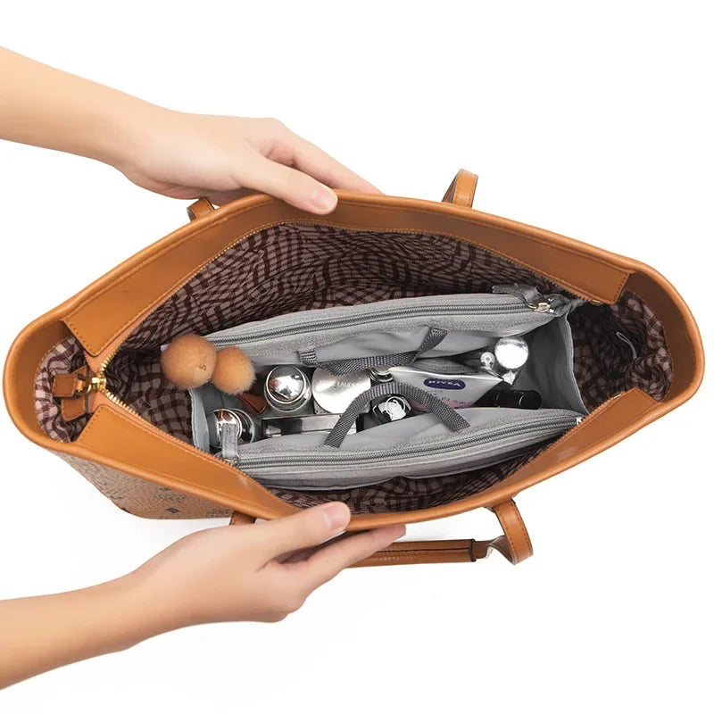 A hand is opening a tan leather purse organizer insert with multiple compartments and silver accessories.
