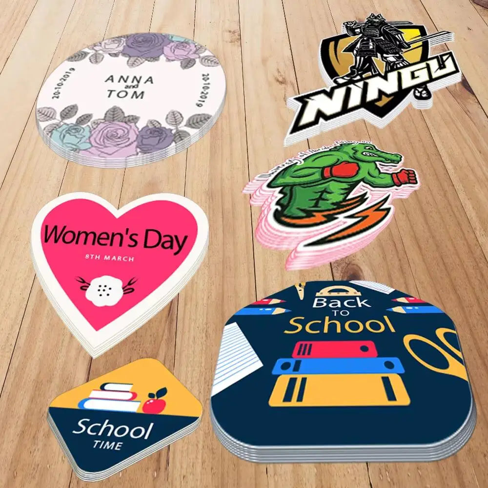 A collection of custom die-cut vinyl stickers featuring names, holidays, and school themes on a wooden surface.