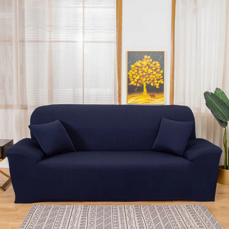 A navy blue silky soft stretchable sofa cover displayed on a couch in a bright room.