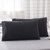 A set of two black microfiber pillowcases resting on a light gray bedsheet.