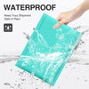 A hand holds a teal waterproof bubble mailer, demonstrating its protection against water spray.