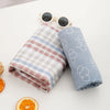 A light blue muslin baby swaddle blanket rolled up next to a pair of sunglasses and an orange slice.