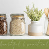 A collection of dried seeds and a bundle of green foliage displayed on a white shelf.