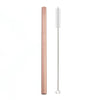 A tall, rose gold reusable stainless steel drinking straw with an attached cleaning brush.