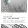 Roll of brushed silver peel-and-stick metal wallpaper shown next to a small jar and a textured background.