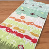 A rectangular green face towel embroidered with various cartoon faces and patterns.
