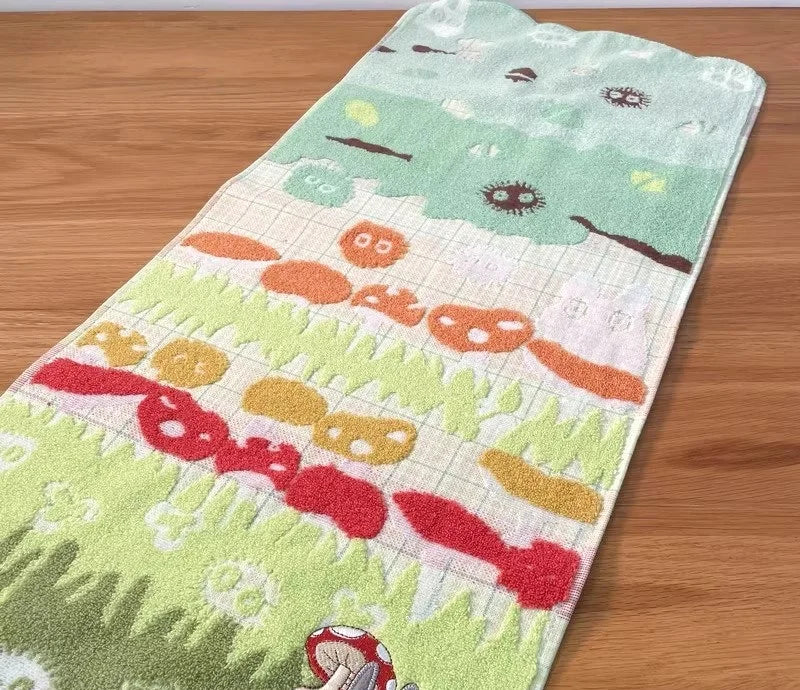 A rectangular green face towel embroidered with various cartoon faces and patterns.