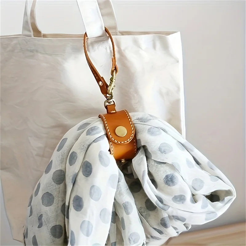 Vintage Lederhandschuhriemen und Handtuchhalter mit weißem Polka-Dot-Stoff vor hellem Hintergrund.