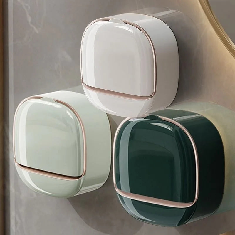 A wall-mounted soap holder with a lid and drainage in white, light green, and dark green colors.