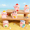 Pink resin pig figurines in various poses displayed on a wooden surface next to sand.