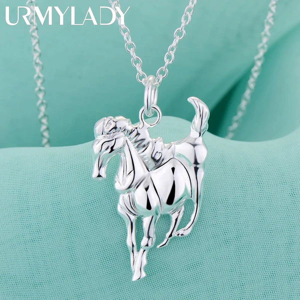 Collier pendentif de cheval en argent sterling sur fond de tissu bleu sarcelle clair.