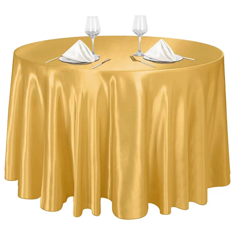 Elegant gold satin round tablecloth set for events featuring glassware and silverware.