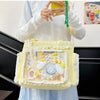 A yellow transparent shoulder bag with white lace trim and decorative elements is held by a person.