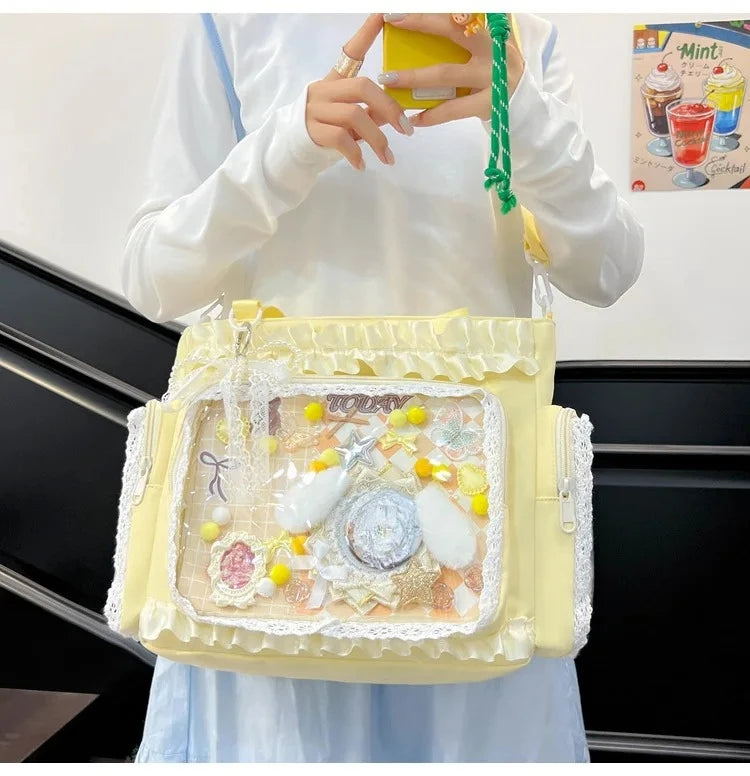 A yellow transparent shoulder bag with white lace trim and decorative elements is held by a person.