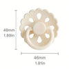 A white silicone baby pacifier with a flower-like design and a ring for the nipple.
