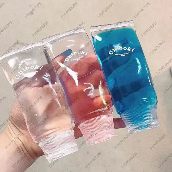 Eine Hand hält drei transparente, klebrige Stressbälle in Rosa-, Violett- und Blautönen.