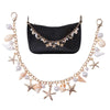 A black faux leather bag with a gold chain featuring starfish and pearl charms.