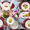 A close-up of a dining table set with food and tableware on reversible non-slip placemats.