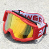 Red and white retro motorcycle sunglasses with yellow night vision lenses resting on a light gray surface.