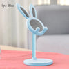 A light blue rabbit-shaped stand for a mobile phone or tablet, shown on a pink surface.
