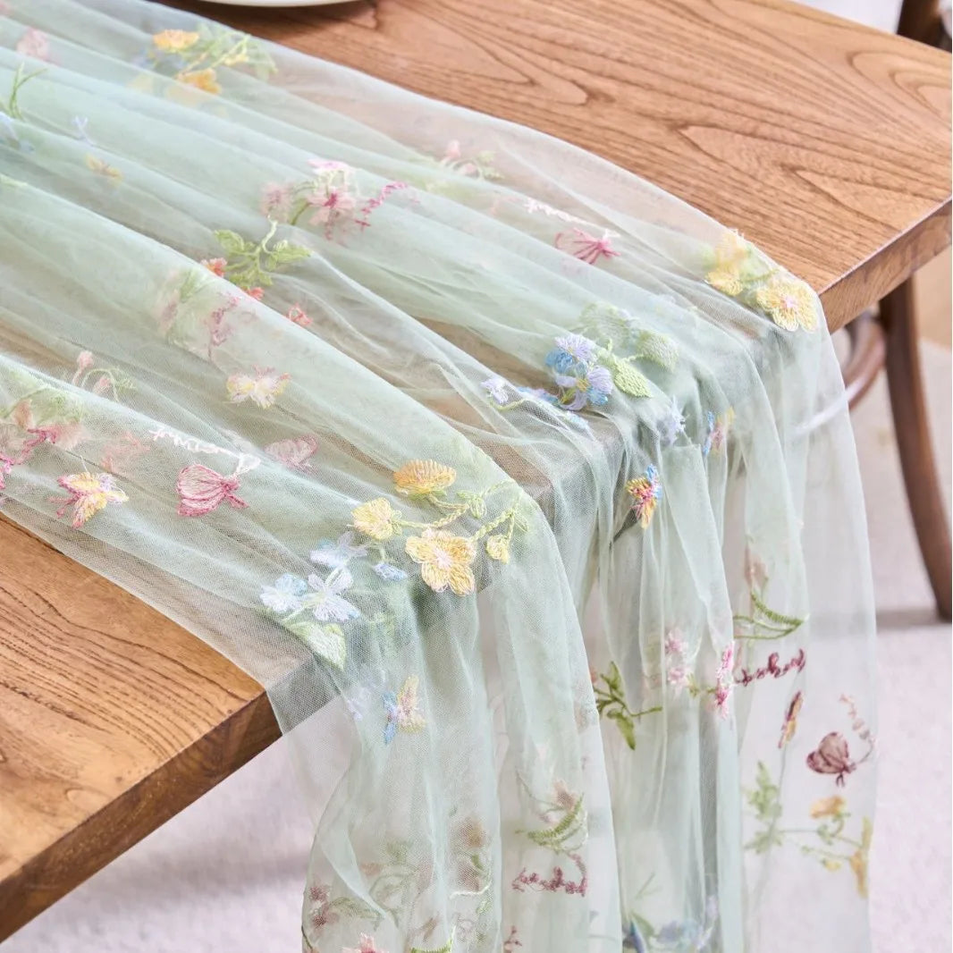 Sheer mint green tulle table runner featuring delicate pink and yellow floral embroidery