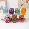A collection of handcrafted crystal owl figurines in various colors and finishes displayed on a white surface.
