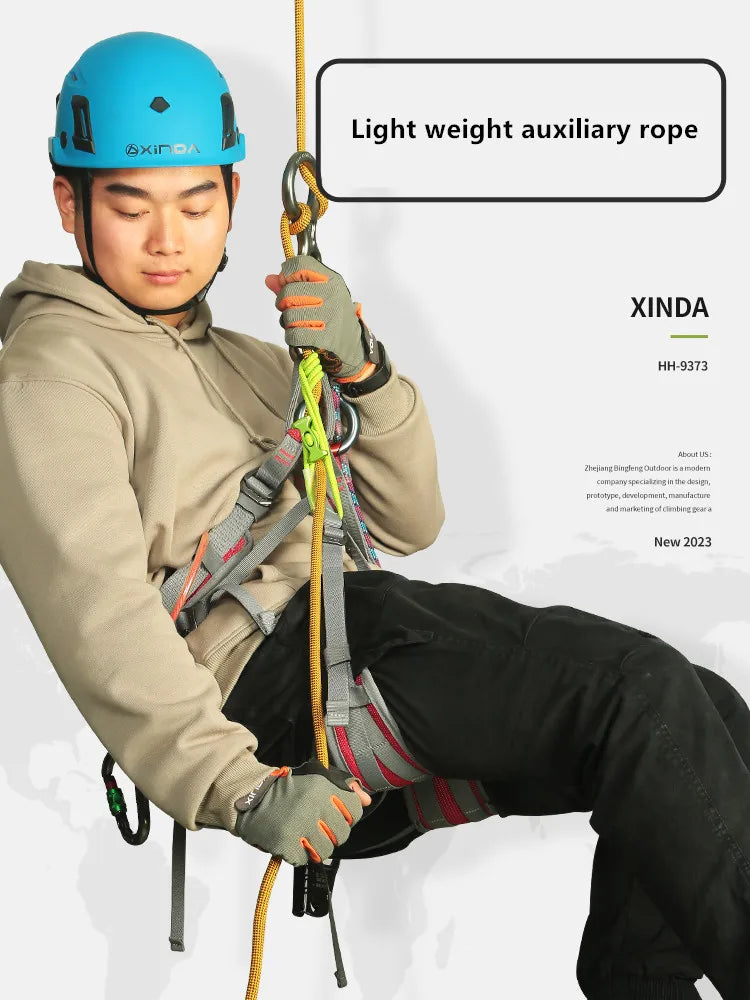 A man wearing a helmet and climbing harness is holding a light weight auxiliary rope for safety.