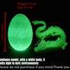 A translucent green dragon figurine with an egg, emitting light in the dark.