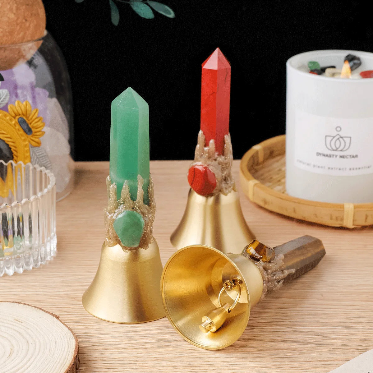 A natural crystal point, colored green and red, is displayed on a brass bell.