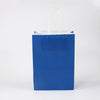A blue paper gift bag with white handles against a white background.