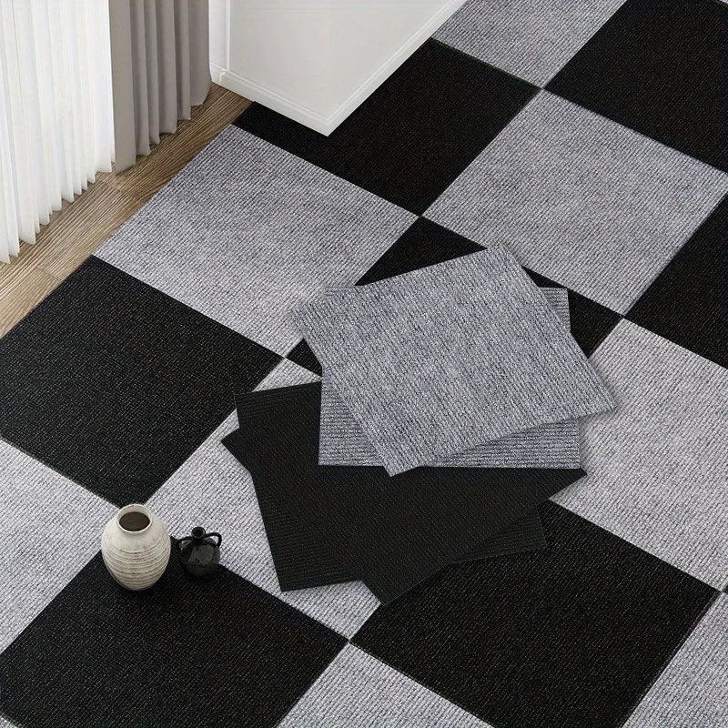 Una pila de baldosas de alfombra gris autoadhesivas sobre una alfombra a cuadros blanco y negro.