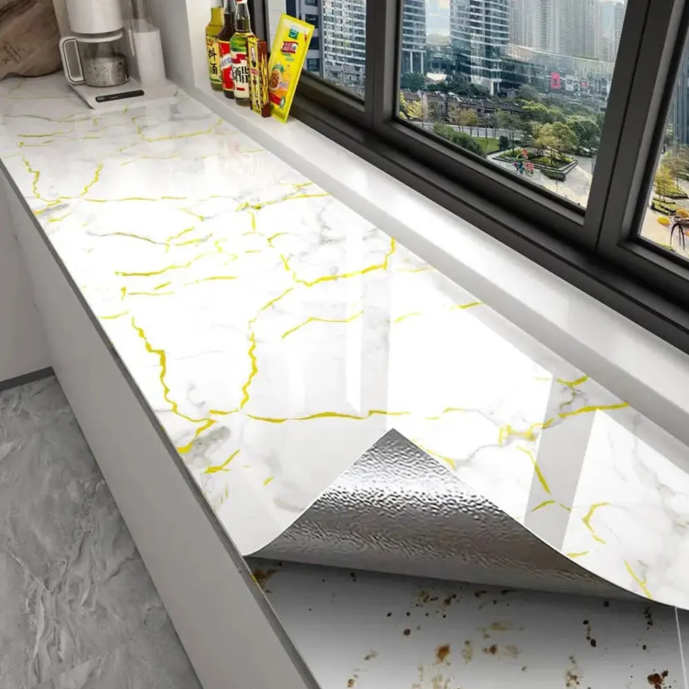 White marble contact paper with yellow veining displayed on a countertop near a window.