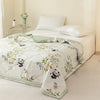 White quilted summer quilt featuring a pattern of pandas and green foliage on a bed.