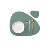 A set of gold-toned cutlery resting on a light green placemat.