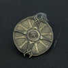 A round, intricately patterned metal ornament resembling a sword, set against a dark background.