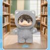 A plush doll of a cat-like character with dark hair and large eyes, sitting in front of wooden bookshelves.