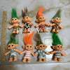 A collection of handcrafted troll doll figurines with brightly colored hair, including green, orange, and pink hues.