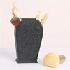 A black coffin-shaped makeup brush holder with a spider web design, holding several makeup brushes.