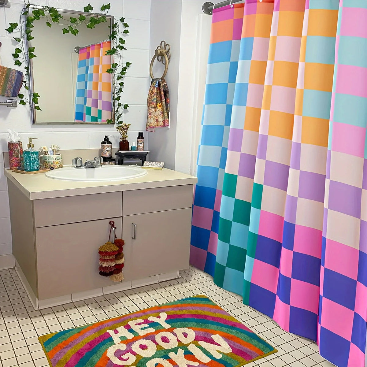 A colorful shower curtain display featuring vertical panels in rainbow plaid patterns and a rug with the text Hey Good Okin.