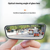 A hand holds a black glass lens mirror showing a wide-angle view of a road with cars and trees.